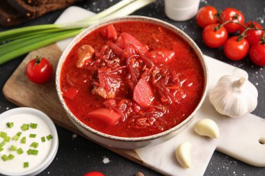 Bir kase lezzetli Ukrayna çorbası ve siyah arka plandaki malzemeler, yakın plan.