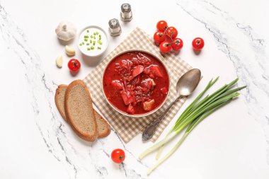 Ekşi kremalı bir kase lezzetli Ukrayna çorbası, yeşil soğan ve beyaz arka planda dilimler.