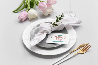 Tebrik kartı ve gri arka planda lale çiçekleri olan güzel bir masa, yakın plan. Anneler Günü kutlaması