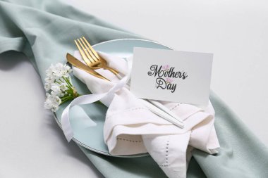 Tebrik kartı ve gri arka planda güzel çiçekler olan şık bir masa. Anneler Günü kutlaması