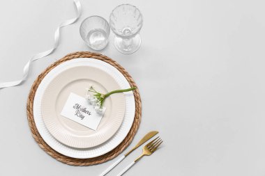 Tebrik kartı ve gri arka planda güzel çiçekler olan şık bir masa. Anneler Günü kutlaması