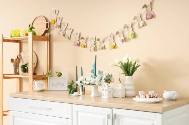 İçinde çiçekler ve bej duvarın yanındaki tezgahta Paskalya süsleri olan festival mutfağı.