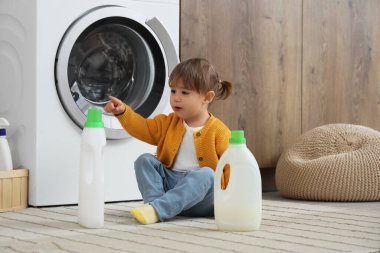 Evde yerde çamaşır deterjanı olan sevimli küçük bir kız. Çocuk tehlikede.