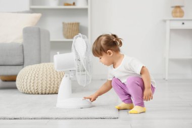 Evdeki elektrikli vantilatörü açan tatlı küçük kız. Çocuk tehlikede.