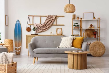 Oturma odasının içinde sörf tahtası, kanepe ve raf ünitesi var.