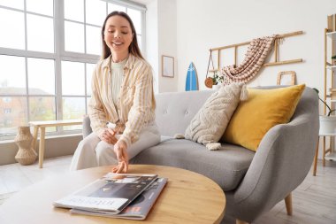 Masadan ve sörf tahtasından dergi alan genç bir kadın.