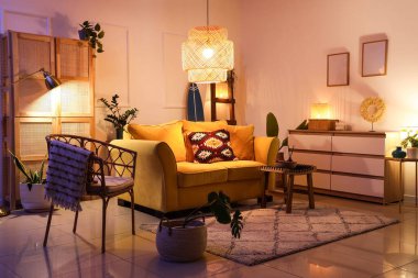 Şık oturma odasının içinde sarı kanepe, parlak lambalar ve akşamları sörf tahtası.