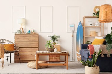 Gri kanepesi, kahve masası, çiçekleri ve sörf tahtası olan şık bir oturma odası.