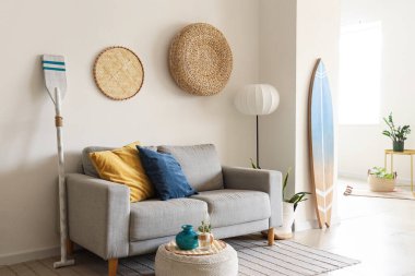 Gri kanepeli, puf ve sörf tahtalı şık bir oturma odası.