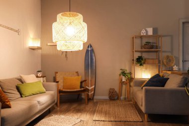 Gri koltukları, parlak lambaları ve akşamları sörf tahtası olan şık bir oturma odası.