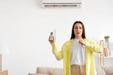 Klima kumandalı genç bir kadın evinde sıcaktan muzdarip.