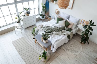 Hafif yatak odasının içinde sörf tahtası, yumuşak bank ve bitkiler var.