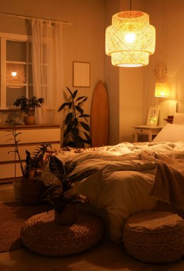 Yatak odasının içinde sörf tahtası, gece parlayan lambalar ve bitkiler var.