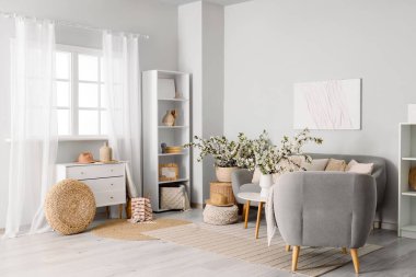 Koltuğu, koltuğu ve çiçekli dalları olan aydınlık oturma odasının içinde.