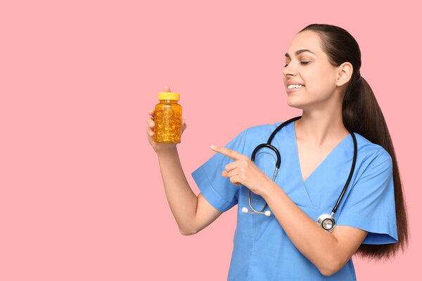 Портрет женщины-врача, указывающей на таблетки на розовом фоне