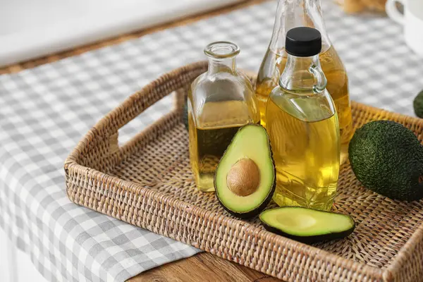 Şişeler dolusu taze yağ ve mutfak tezgahında avokado olan hasır tepsi.