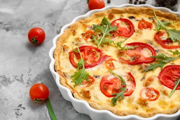 Gri arka planda roka yapraklı lezzetli domatesli tart, yakın plan.