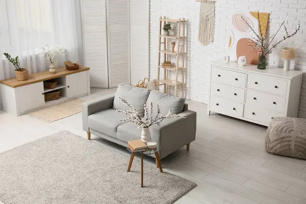 Oturma odasının içinde kanepe ve çiçek açan dallar var.