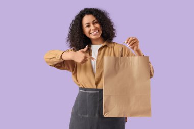 Kadın Afro-Amerikalı işçi leylak arkaplanındaki kese kağıdını işaret ediyor. Yemek dağıtım servisi.