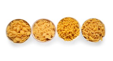 Beyaz arka planda farklı tipte çiğ makarna olan kaseler