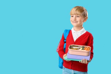 Beslenme çantası ve mavi arka plan kitapları olan küçük bir okul çocuğu.