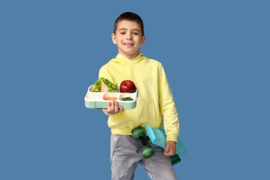 Sefertası ve mavi arka planda kaykayı olan küçük bir çocuk.