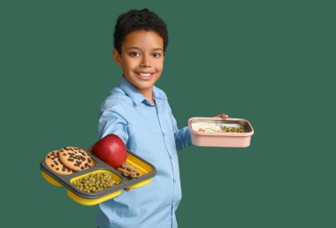 Yeşil arka planda beslenme çantaları olan sevimli Afro-Amerikan öğrenci.