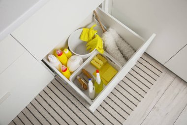 Modern mutfakta temizlik malzemeleri, sepet ve kova dolu çekmece.