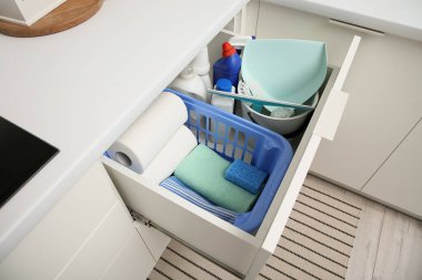 Modern mutfakta temizlik malzemeleri, kağıt havlular ve sepetlerle dolu bir çekmece.