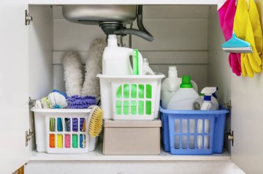 Mutfakta lavabonun altında farklı temizlik malzemeleri olan sepetler.