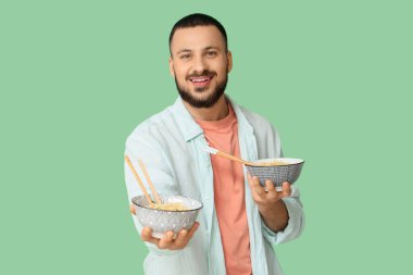 Yeşil arka planda lezzetli ramen yiyen genç bir adam.