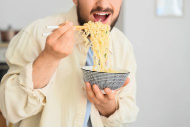 Genç adam mutfakta lezzetli ramen yiyor, yakın plan.