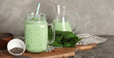 Mason kavanozu taze ıspanaklı smoothie ve gri arka planda chia tohumlu kase.