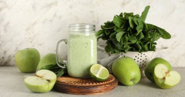 Mason kavanozu beyaz arka planda limonlu ve elmalı taze ıspanaklı smoothie.