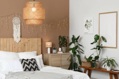 Şık bir yatak odası, farklı bitkiler, parlak bir çelenk ve büyük bir yatak.