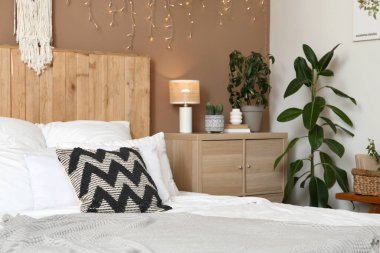 Şık bir yatak odası, farklı bitkiler, parlak bir çelenk ve büyük bir yatak.