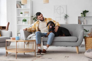 Dobermann 'ın köpeği evdeki kanepede oturan genç adam.