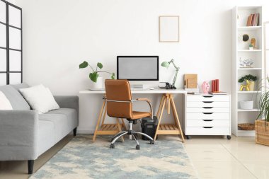 Çalışma yeri, kanepesi ve raf ünitesi olan aydınlık oturma odasının içinde.