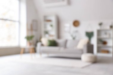 Gri kanepe, raf üniteleri ve bitkilerle aydınlık oturma odasını bulanık görmek