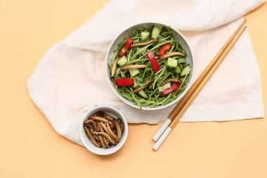 Taze salata ve turuncu arka planda kızarmış kurtçuk.