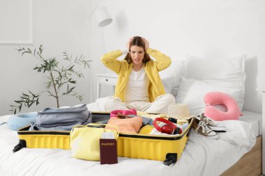 Stresli kadın turist yatak odasında bavul hazırlıyor.