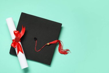 Mezuniyet şapkası ve turkuaz arka plan diploması.