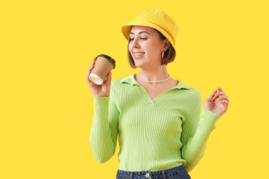 Sarı arka planda diş teli ve kahve fincanı olan genç bir kadın.