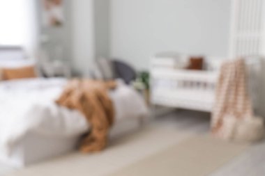 Yatak ve bebek karyolası olan odanın bulanık görüntüsü