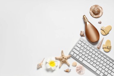 Beyaz arkaplanda güneş kremi ve plaj dekoru olan bilgisayar klavyesi