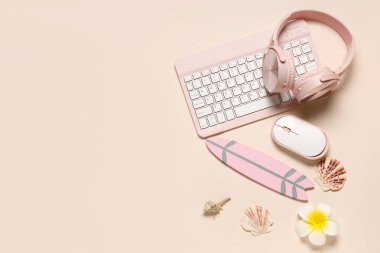 Bej arka planda kulaklıklı bilgisayar klavyesi, fare ve plaj dekoru