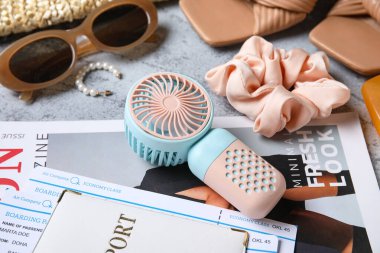 Moda dergisi, pasaport, bilet ve arka planda mini fan bulunan kadın yaz aksesuarları.