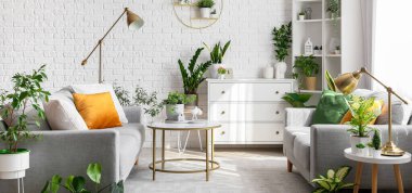 Oturma odasının içinde kanepeler, masalar ve bitkiler var.