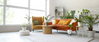 Yeşil çiçekleri, kanepesi ve koltuğu olan bir oturma odası.