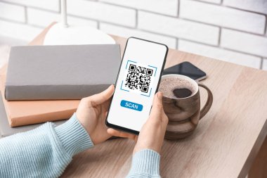 Woman using modern mobile phone at table, closeup